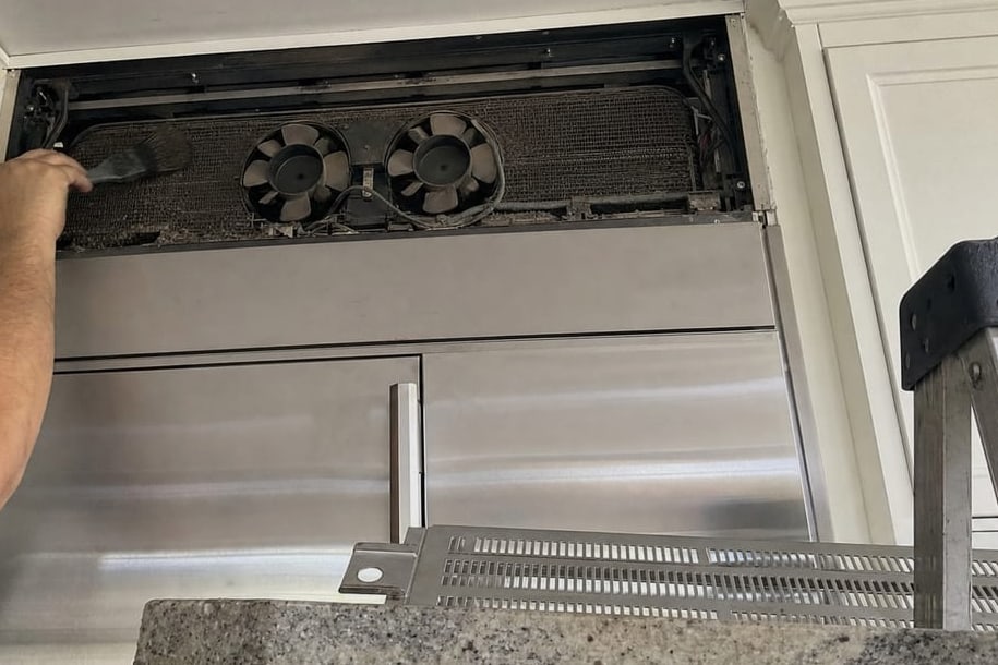 Upper grille of a built-in unit opened to show the condenser coil and fans behind it