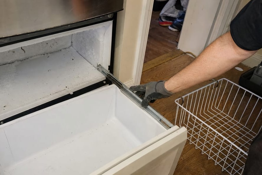 Sub-Zero built-in refrigerator with the lower kickplate removed for condenser cleaning